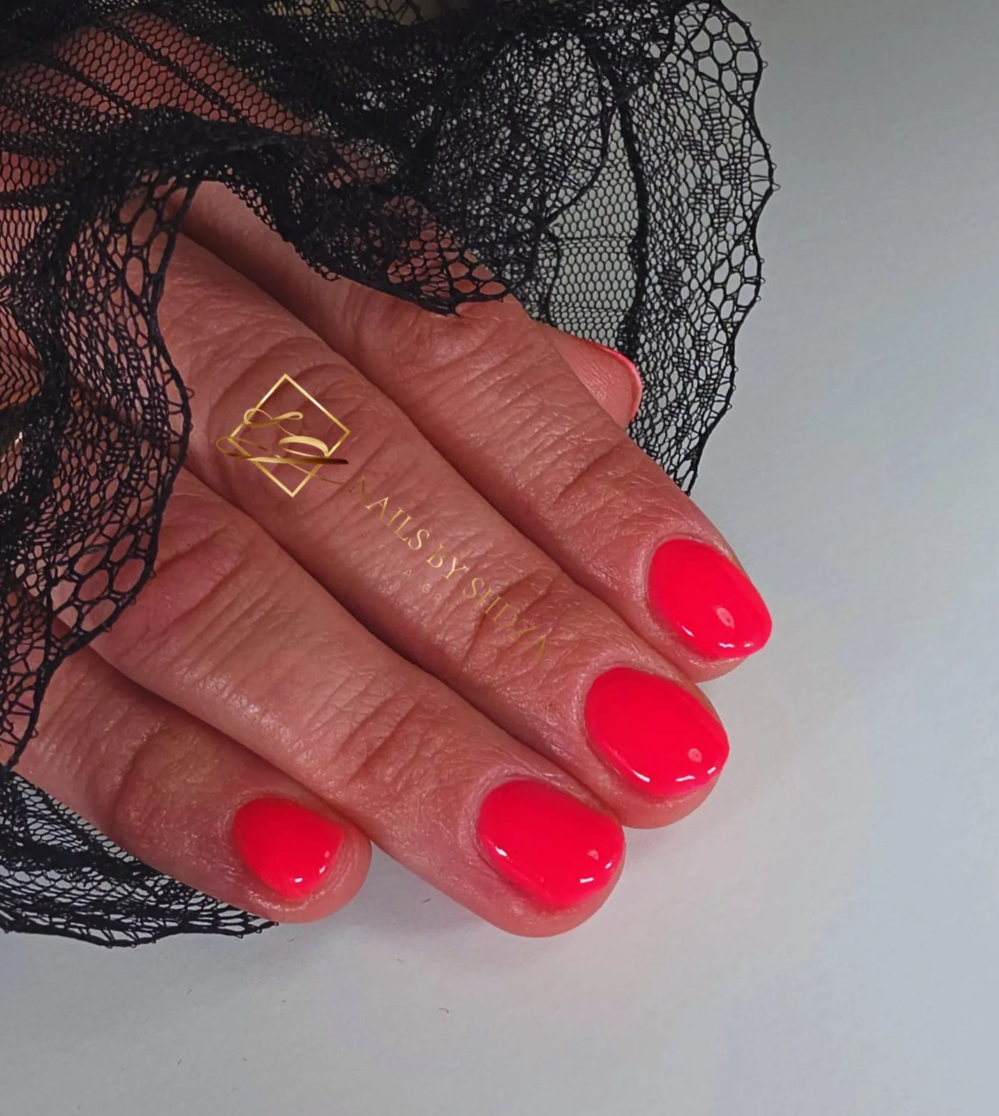 Coral pink gel nails on black lace